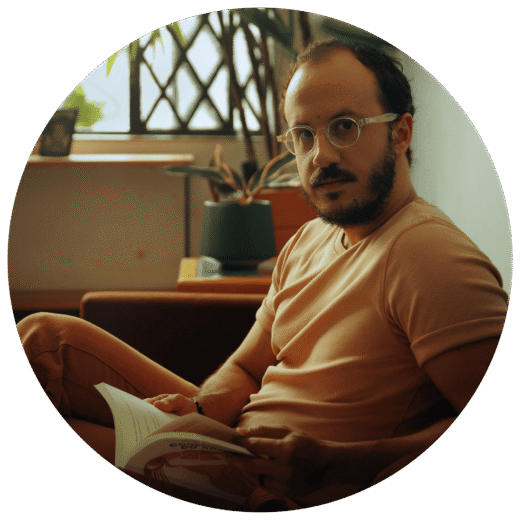 Professor Rafael Tosta lendo em retrato circular com rosto borrado.